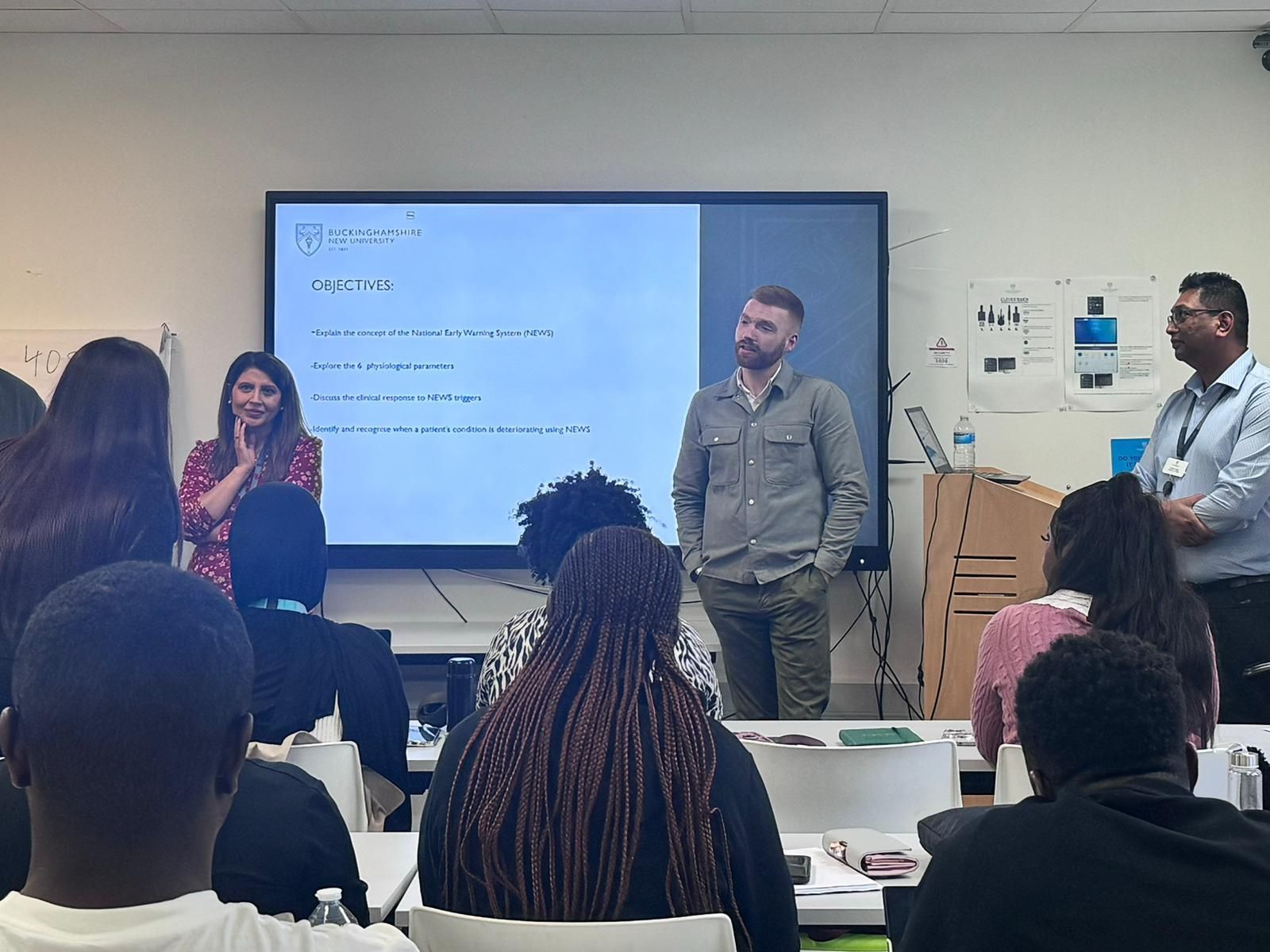 A busy classroom with people standing at the front presenting to the audience