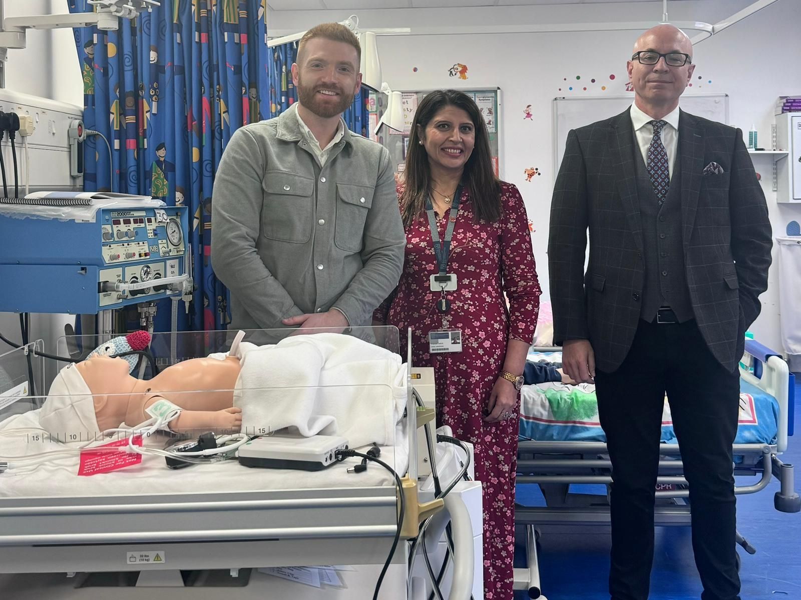 Two men and a woman standing next to a dummy nursing child