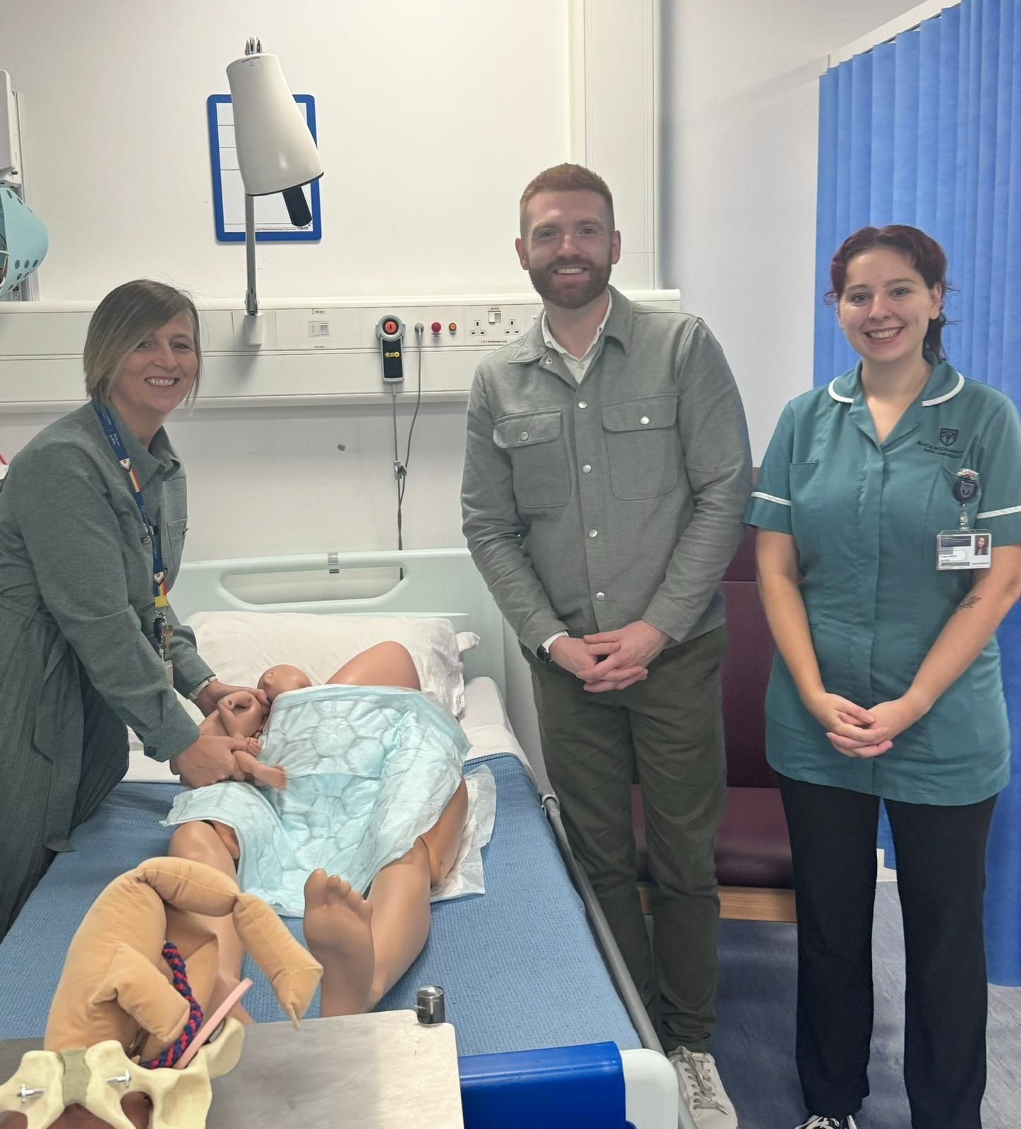 Three people surrounding a dummy patient 