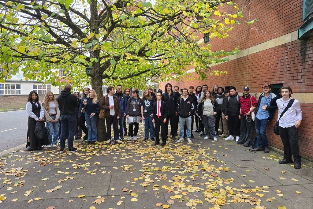 A large group of Computer Games Development students stood together outside in front of a tree