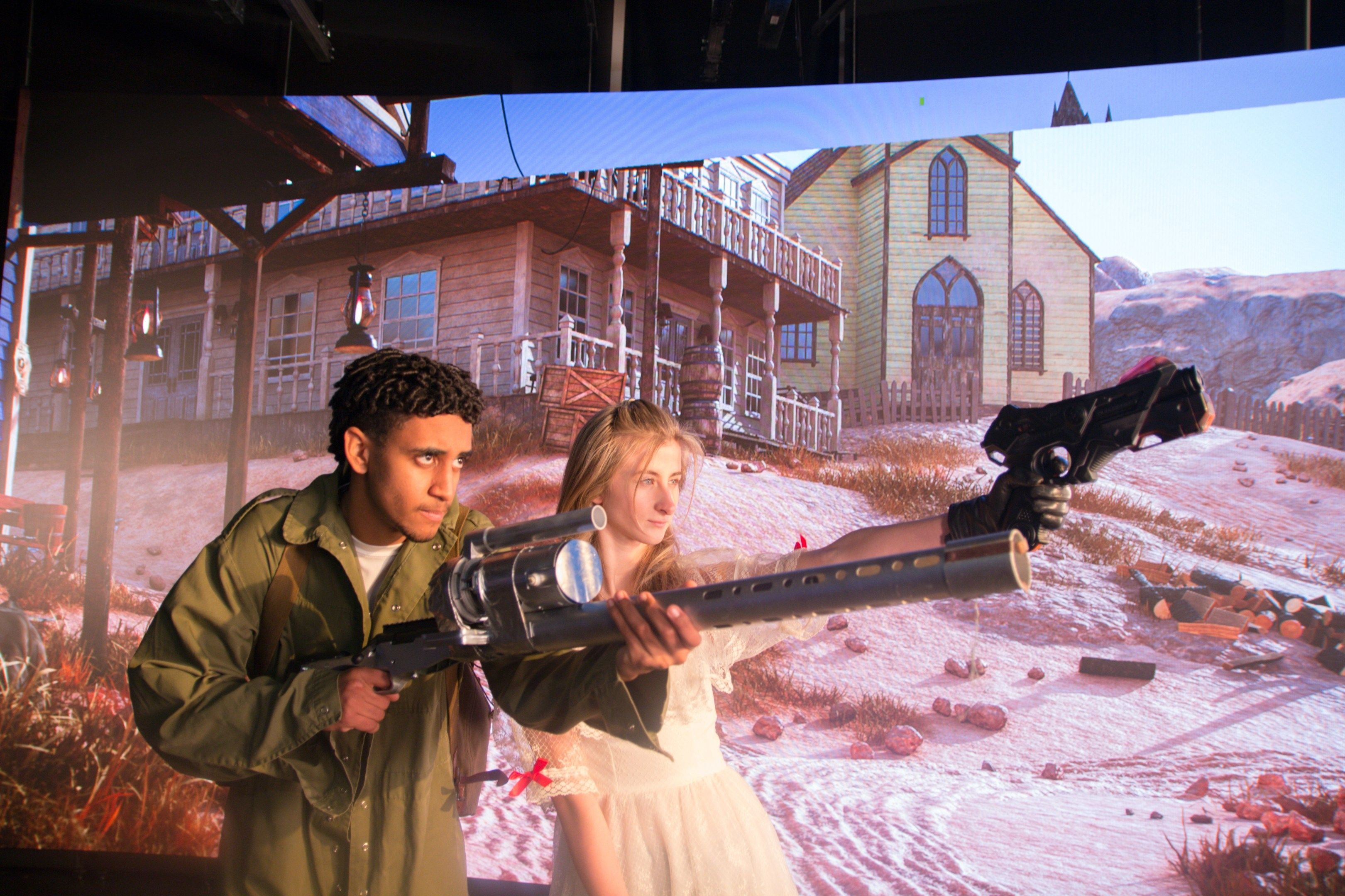 Two students acting, while holding props in front of an LED screen