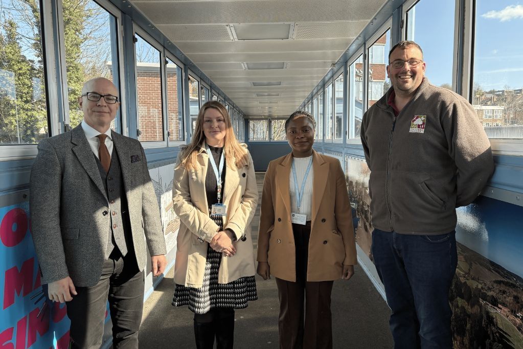 Four people stood on a bridge posing for a photo.