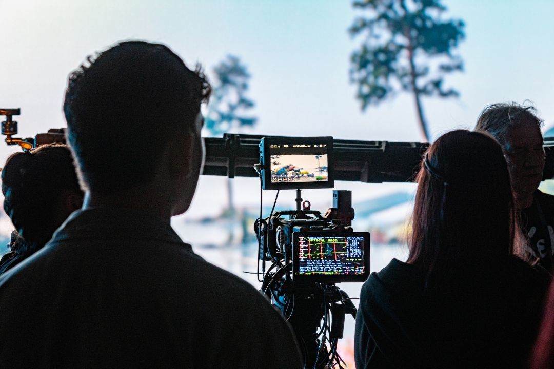 Silhouettes of two students facing a camera which is focusing on an LED screen wall.