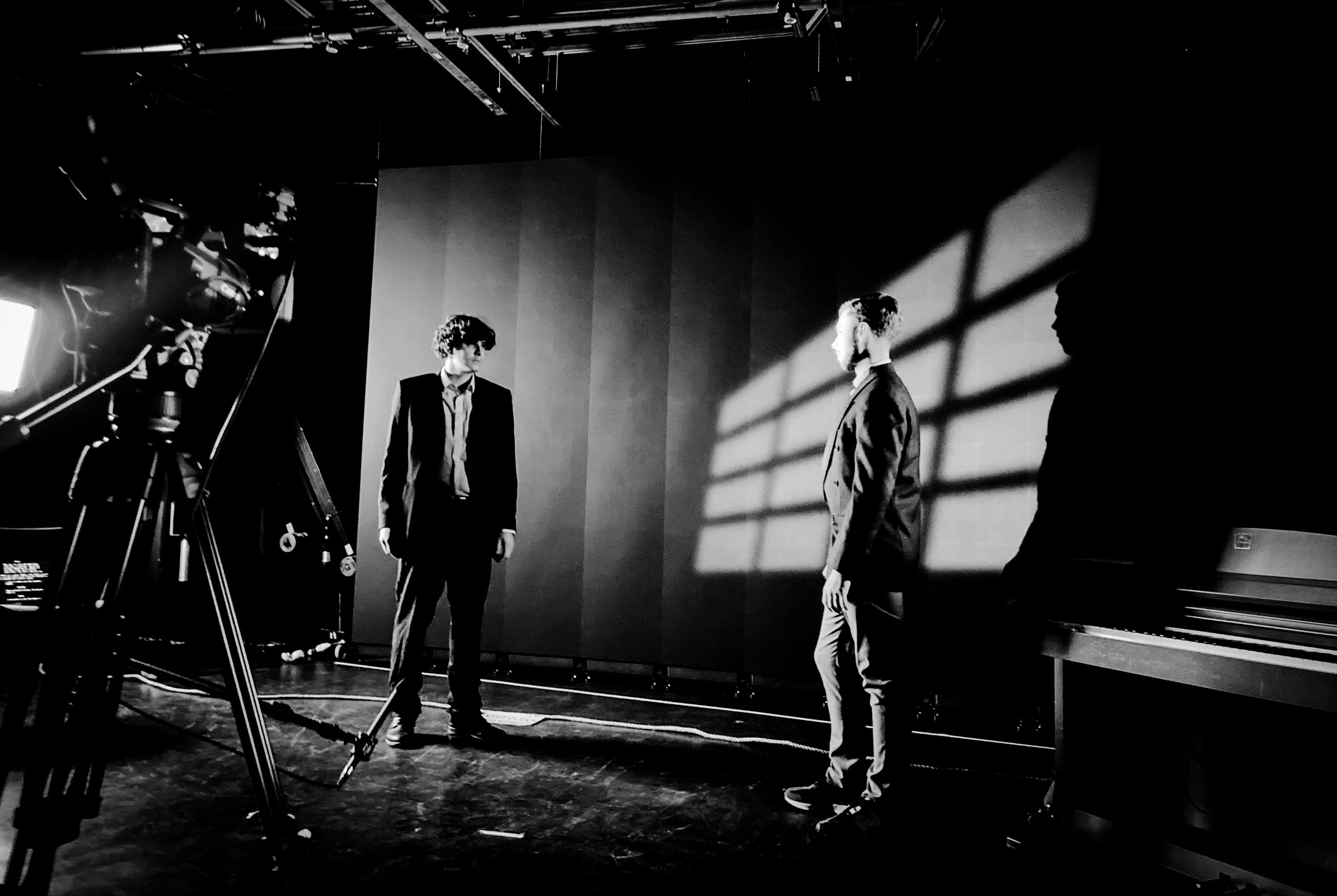 Picture of two students facing each other in a film studio with film noir lighting