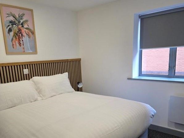 Interior of a bedroom in Alex House showing bed, wall art, window and radiator