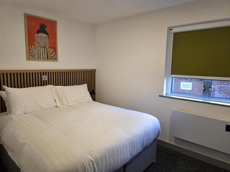 Interior of a bedroom in Alex House showing bed, wall art, window and radiator