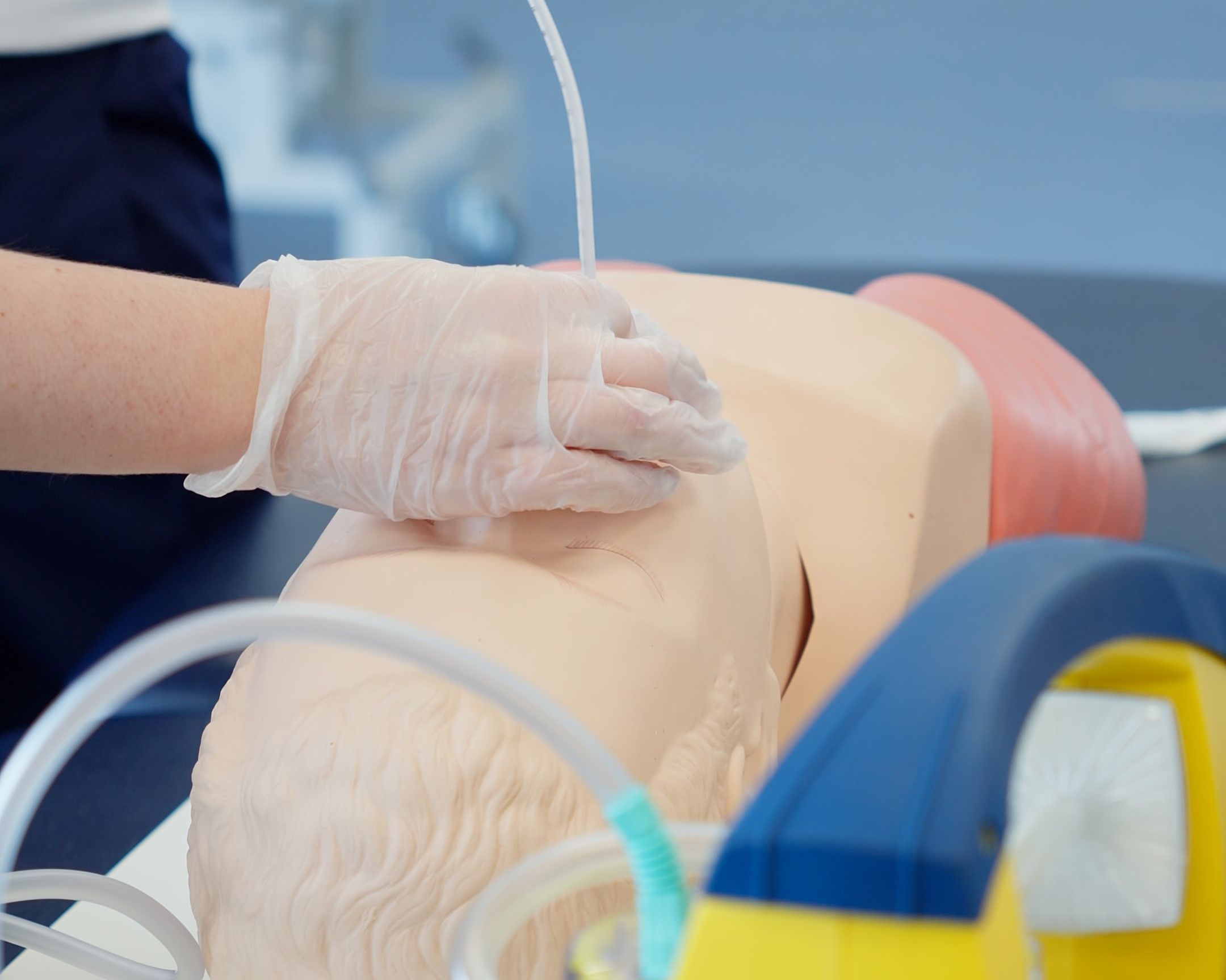 Close-up of a physiotherapy student with protective gloves practicing an airway management procedure on a training mannequin head