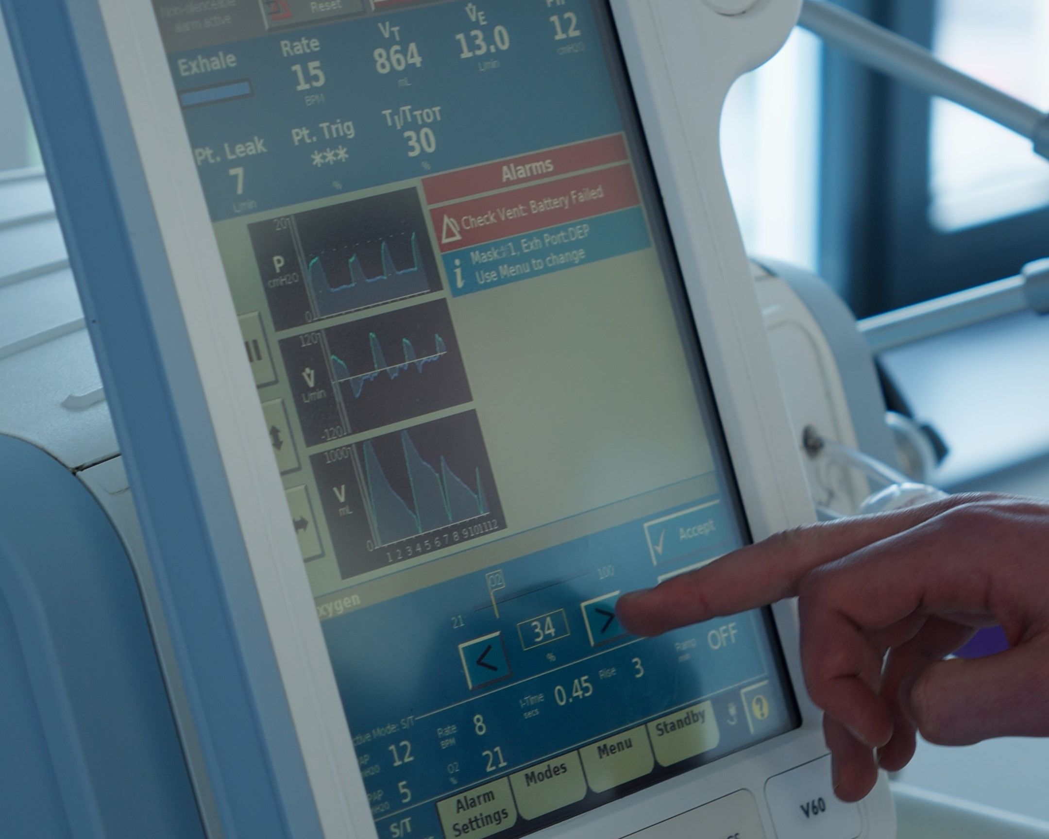 Close-up of a lecturer adjusting settings on a medical ventilator monitor screen