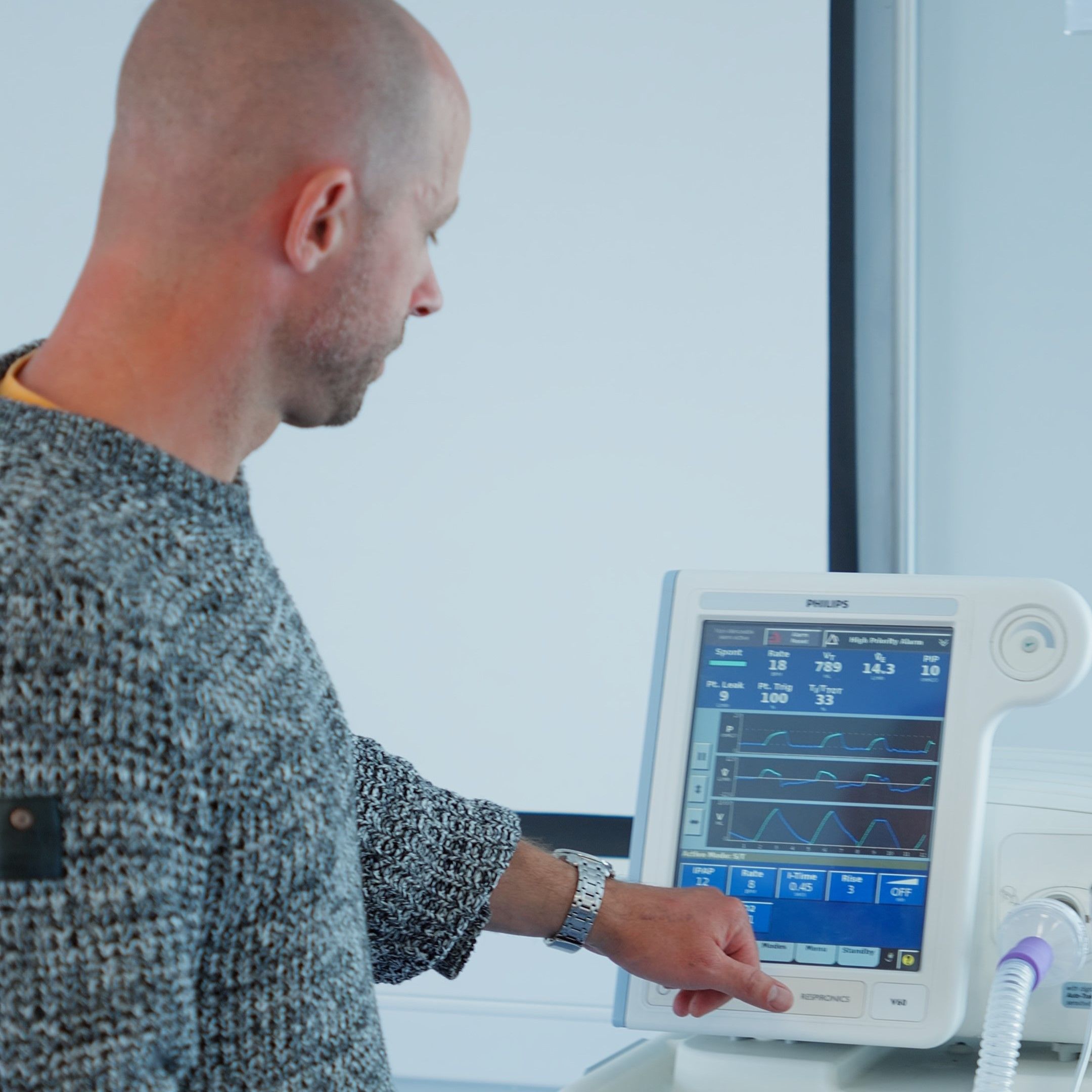Physiotherapy lecturer stood up in a classroom and pushing the button on a clinical machine.